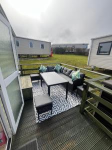a patio with a couch and a table on a deck at Willows Retreat in Reighton