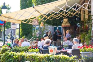 Eine Gruppe von Menschen sitzt in einem Restaurant unter einem Regenschirm in der Unterkunft MERICI Hotel Sittard in Sittard