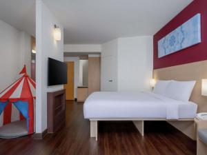a bedroom with a white bed and a flat screen tv at Ibis Bangkok Riverside in Bangkok