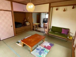 a living room with a table and a green couch at Guesthouse Papaya in Shimoda +34 photos
