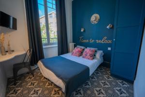 a blue room with a bed and a desk and a window at Hôtel de la Croix-Rousse in Lyon