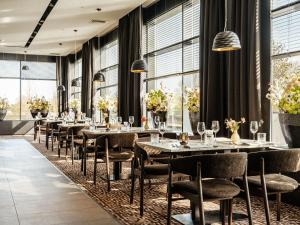 a dining room with tables and chairs and windows at Van der Valk Hotel Dordrecht in Dordrecht