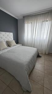 a bedroom with a large bed with white curtains at the Beach House in A Pobra do Caramiñal +10 photos