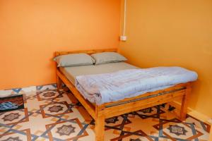 a wooden bed in a room with an orange wall at Jigyasa Homestay in Almora