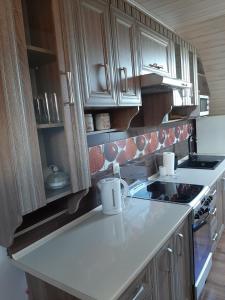 a kitchen with wooden cabinets and a white counter top at Pod żurawiem II in Szwalk