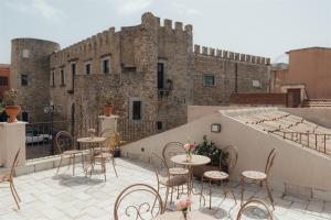 a patio with tables and chairs in front of a castle at Locanda delle rose in Roccavaldina