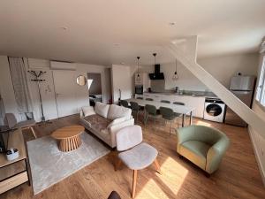 a living room with a couch and chairs and a kitchen at Résidence la Plage in La Bourboule