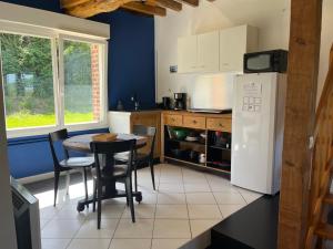 a kitchen with a table and a white refrigerator at Le champ de l alouette in Bec-de-Mortagne +18 photos