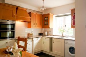 a kitchen with white cabinets and a sink and a window at Edwardian Cottage in beautiful surroundings with hot tub in Slinfold +25 photos