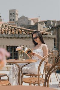 a woman sitting at a table reading a book at Locanda delle rose in Roccavaldina