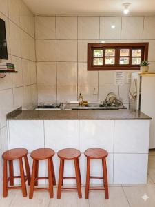 a kitchen with three wooden stools in front of a counter at Residencia Siqueira in Garopaba