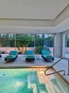 a house with a swimming pool with blue chairs and a swimming pool at Elitis House - Suite & Spa in Nova Milanese