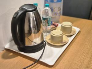 a tea kettle on a tray with cups on a table at GH Brother Eureka in Guwahati