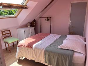 a bedroom with a bed with a chair and a window at Le champ de l alouette in Bec-de-Mortagne
