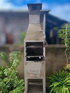 a grill sitting in a garden with some plants at Residencia Siqueira in Garopaba