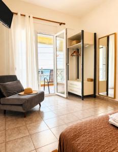 a bedroom with a couch and a chair and a balcony at Starry Coast Apartments in Nea Potidaea