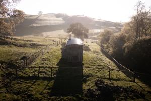 a small building in a field next to a fence at The Wagon, rustic off grid experience in Ashbourne +23 photos