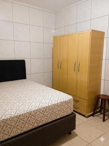 a bedroom with a bed and a wooden cabinet at Residencia Siqueira in Garopaba