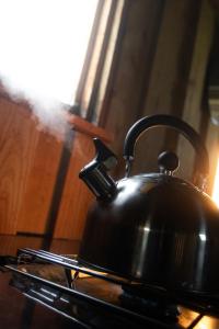 a tea kettle sitting on top of a stove at The Wagon, rustic off grid experience in Ashbourne