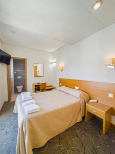 a hotel room with a bed with towels on it at Hotel 13 de Outubro By Umbral in Fátima +47 photos