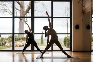 two people doing yoga in a room with windows at ADLER Thermae in Bagno Vignoni
