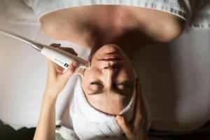 a woman getting her eyebrows cut with a pair of scissors at ADLER Thermae in Bagno Vignoni