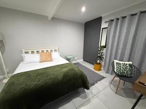 a bedroom with a bed and a chair and a window at The Apartment on Risa in Emerald Hill