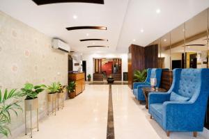 a lobby of a hospital with blue chairs and plants at Skylark Hotel by Gabrian Hotels in Gurgaon