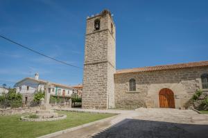 a stone building with a clock tower in a yard at Pisito de Pueblo I I in Navaluenga