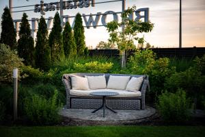 a couch sitting in a garden with a table at Hotel Uniejów in Uniejow