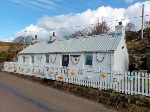 a white house with a fence in front of it at The Captains in Bettyhill