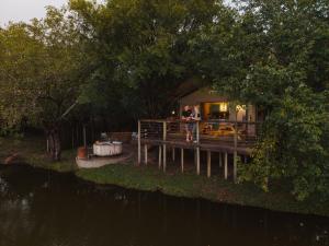 two people standing on a dock next to a house at AfriCamps Hoedspruit in Hoedspruit
