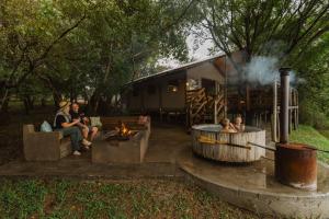 a group of people sitting around a fire in front of a trailer at AfriCamps Hoedspruit in Hoedspruit