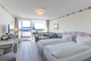 a bedroom with two beds and a living room at Hotel Wiking Sylt in Westerland