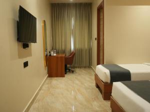 a hotel room with two beds and a desk and a television at Shreeja Central in Bhawānipatna