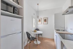 a white kitchen with a small table and chairs at Suite 3 in Mahón