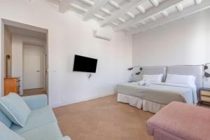 a white bedroom with two beds and a tv at Suite 3 in Mahón