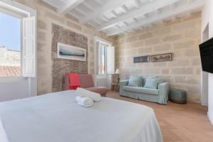 a bedroom with a white bed and a living room at Suite 3 in Mahón