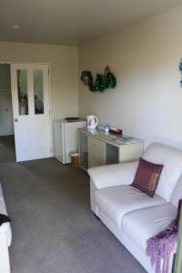 a living room with a white couch and a desk at The Harbour View Tairua in Tairua