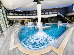 a large pool with water fountain in a building at Logis Hôtel & Spa Marina d'Adelphia in Aix-les-Bains