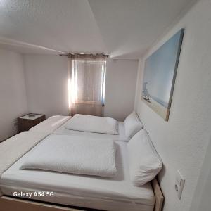 a bedroom with a bed with white sheets and a window at Gasthaus Sonne 3 in Braunsbach