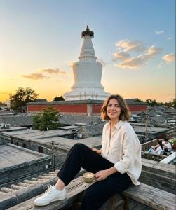 a woman sitting on a bench in front of a temple at Beijing Templeside Courtyard Hotel 丨 3 metros to the Square丨Free laundry, personalized services large terrace in Beijing