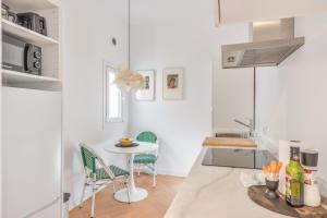 a white kitchen with a small table and chairs at Suite 2 in Mahón