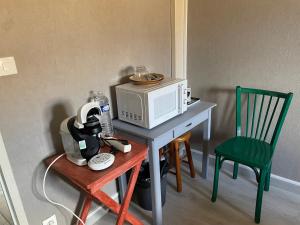 a kitchen with a table with a microwave and a chair at Maison avec balcon in Saint-Hilaire-Petitville