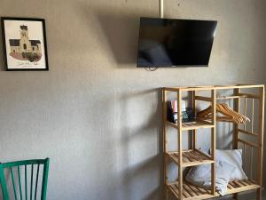 a television on a wall with a book shelf at Maison avec balcon in Saint-Hilaire-Petitville