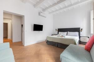 ein Schlafzimmer mit Bett, Fernseher und Sofa in der Unterkunft Suite 1 in Maó