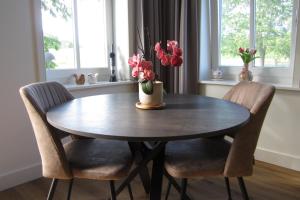 a dining room table with two chairs and a vase of flowers at Aan de Dijk in Edam