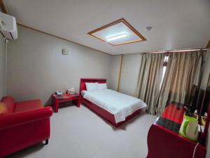 a bedroom with a bed and a couch and a tv at Happy Hotel in Jeju