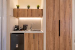 a kitchen with wooden cabinets and a sink at Fragos Garden Studios in Kyllini +35 photos