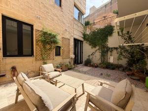 an outdoor patio with chairs and tables and a building at Cosy home in Three Cities in Taʼ Penza